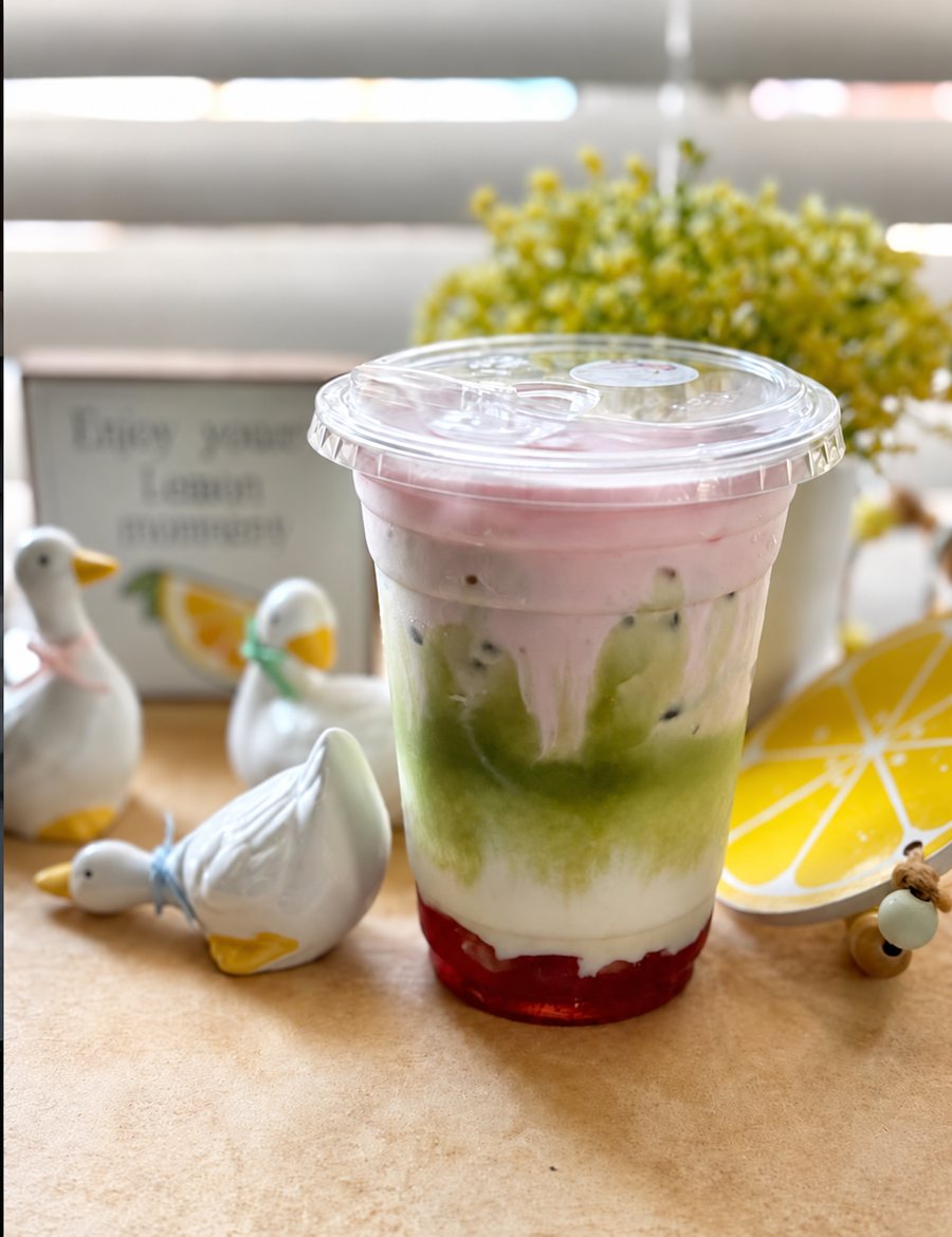 Layered drink with strawberry at the bottom, matcha in the middle and pink cold foam on top